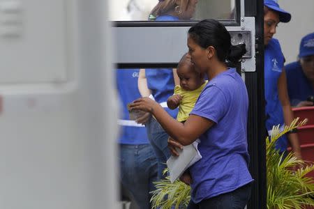 A woman and her son step into a bus, bound to take deportees from U.S. to a bus station, at the international airport in San Pedro Sula, northern Honduras July 14, 2014. REUTERS/Jorge Cabrera