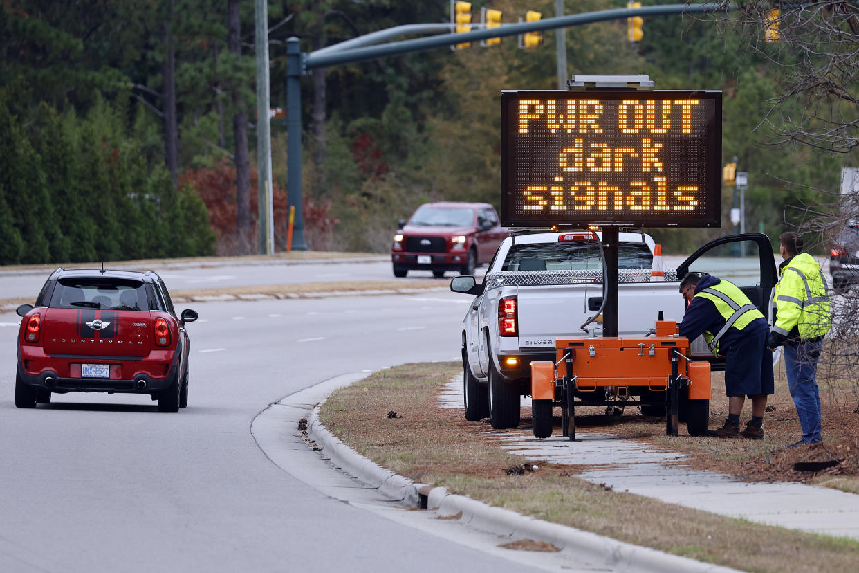 Workers set up an automated display by a highway saying: PWR OUT dark signals.