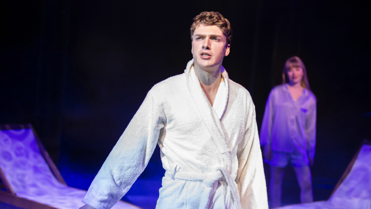 A man on stage in a white bathrobe