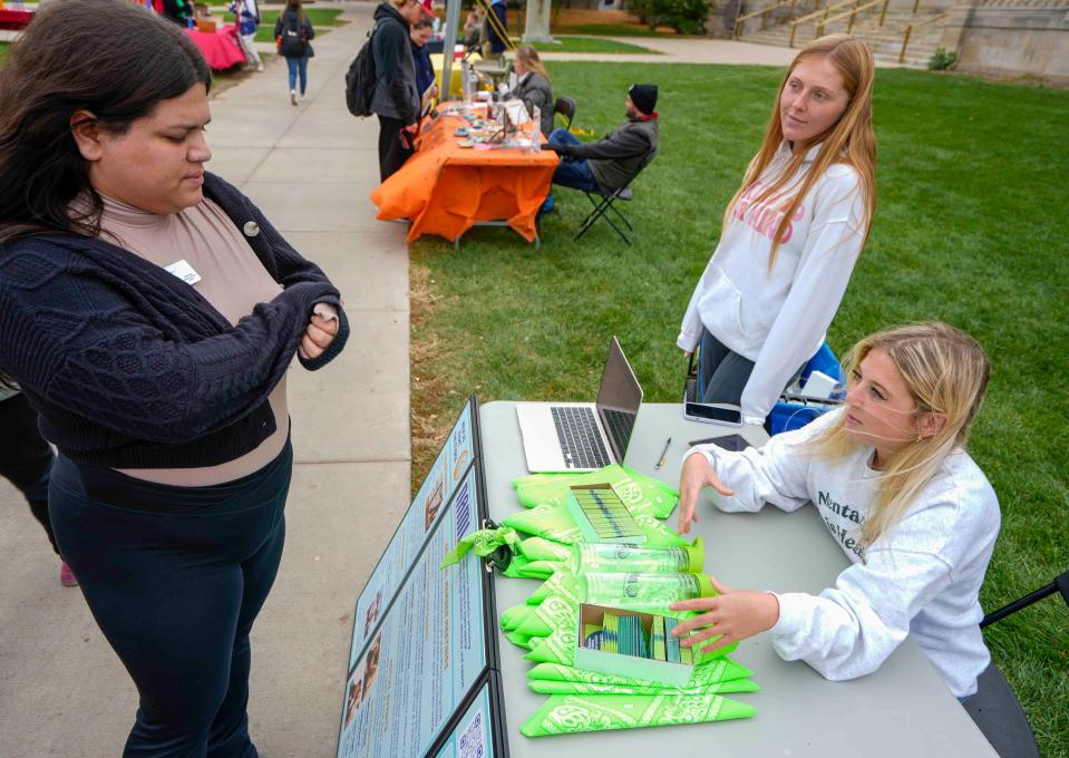 Katherine Zimmerman, co-president of the UW-Madison chapter of the National Alliance of Mental Illness, middle, and Ava Heyrman educate Wynter Zamora about the Green Bandana Project at a mental health fair in October. A green bandana tied around someone's backpack is a symbol of solidarity, with the bandana's owner carrying mental health resources for anyone in need.