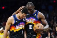 Phoenix Suns guard Devin Booker (1) is congratulated by center Bismack Biyombo (18) after scoring against the Indiana Pacers during the second half of an NBA basketball game Saturday, Jan. 22, 2022, in Phoenix. (AP Photo/Ross D. Franklin)