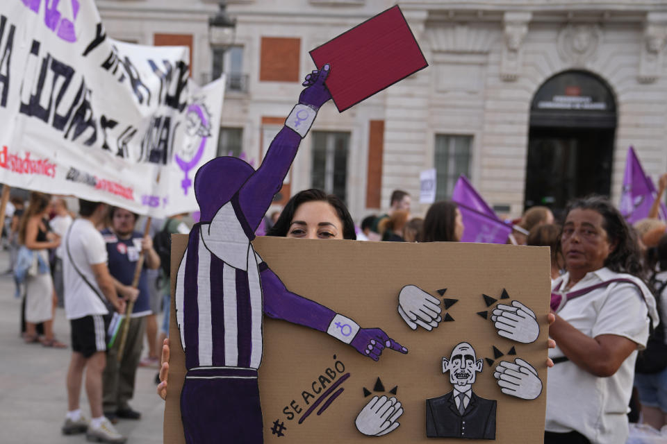 A woman holds a board depicting Spanish soccer federation President Luis Rubiales being shown a red card and hands applauding, during a protest against Rubiales in Madrid, Spain, Friday, Sept. 1, 2023. A Spanish government legal panel is opening a case against suspended soccer chief Luis Rubiales who has come in for a storm of criticism and calls for his resignation for kissing a player on the lips without consent after Spain won the recent Women's World Cup final in Sydney. (AP Photo/Paul White)