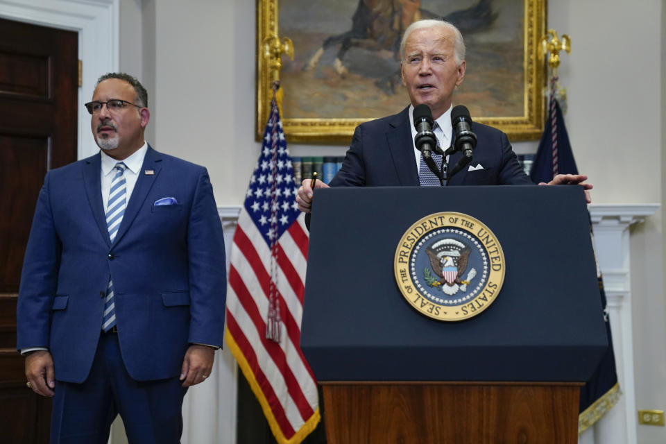 FILE - President Joe Biden speaks as Education Secretary Miguel Cardona listens at the White House, June 30, 2023, in Washington. Biden is traveling to Wisconsin Monday, April 8, 2024, to announce details of a new plan to help millions of people with their student loan debt. Last year, the U.S. Supreme Court foiled Biden's plan to provide hundreds of billions of dollars in student loan debt relief to millions. The visit comes a week after primary voting in the Midwest battleground state highlights weakness for him and Republican challenger Donald Trump. (AP Photo/Evan Vucci, File)