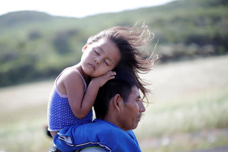 Rosendo Noviega, a 38-year-old migrant from Guatemala, part of a caravan of thousands from Central America en route to the United States, holds his daughter Belinda Izabel as he walks along the highway to Juchitan from Santiago Niltepec, Mexico, October 30, 2018. REUTERS/Ueslei Marcelino