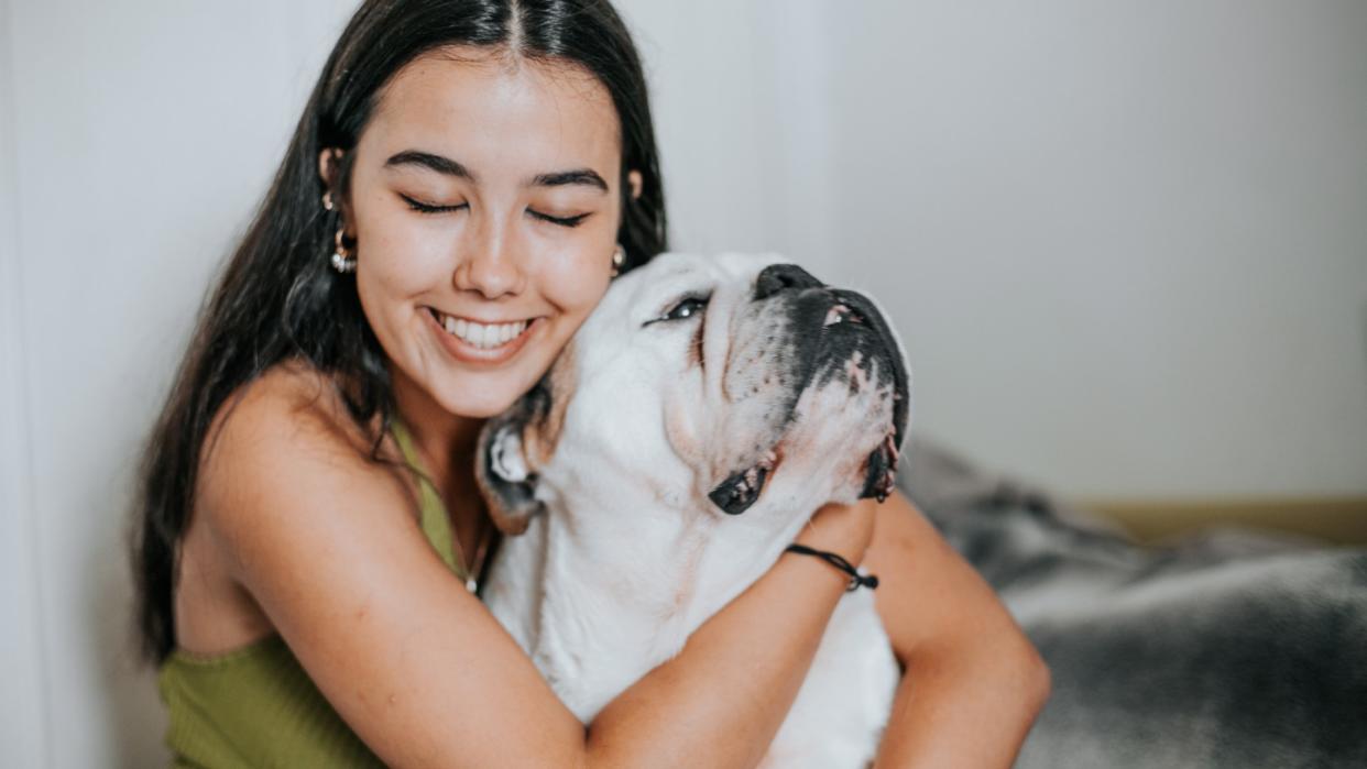 a smiling woman hugs her English bulldog