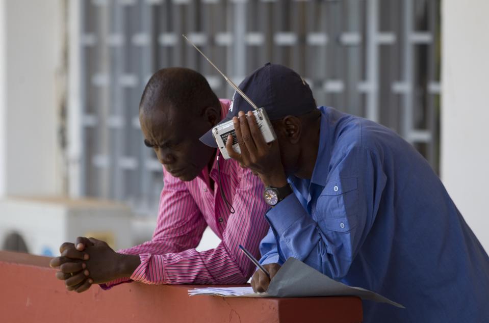 Men listen to a live broadcast of the proceedings of the parliamentary elections at the national assembly in Bangui