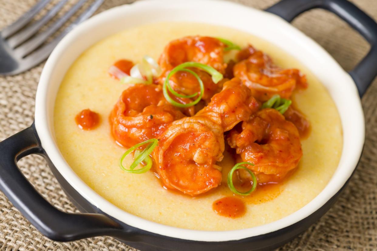 Soft polenta topped with prawns in tomato and chili sauce garnished with spring onion.