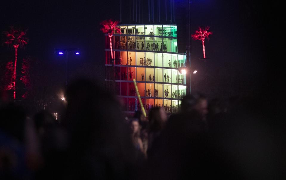 Music fans walk in a colorful multilevel art installation building at night.