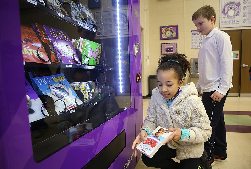 Pickerington Elementary third-grader London Towns, eight,  gets her book from the new book vending machine Feb. 9 as Micah Haverfield waits his turn.