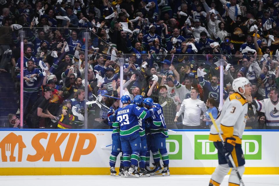 Vancouver Canucks' Dakota Joshua, back centre, is mobbed by his teammates after scoring his first goal as Nashville Predators' Jeremy Lauzon (3) skates to the bench during the third period in Game 1 of an NHL hockey Stanley Cup first-round playoff series, in Vancouver, on Sunday, April 21, 2024.  (Darryl Dyck/The Canadian Press - image credit)