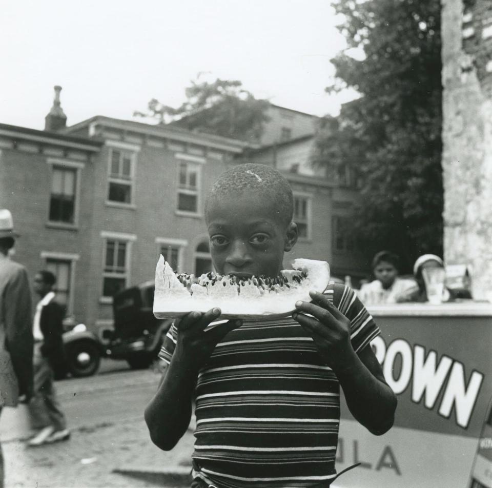 A boy eats a watermelon during the Big Quarterly in August 1939 in Wilmington, Delaware.