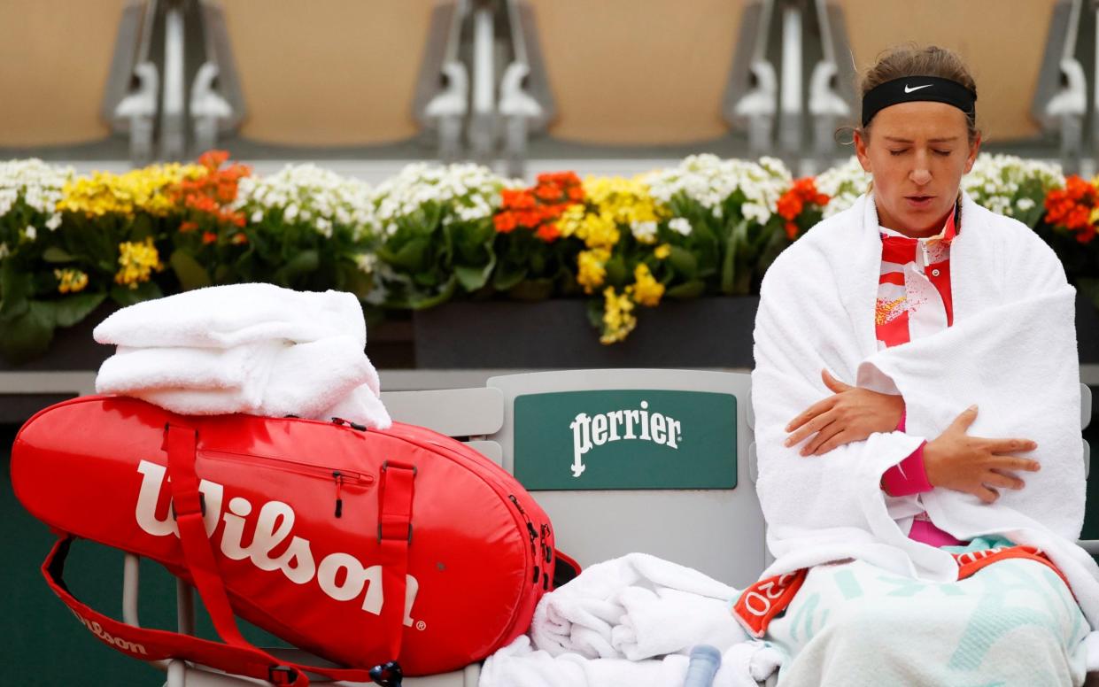 Victoria Azarenka wraps up warm on court waiting for the rain to pass - Reuters