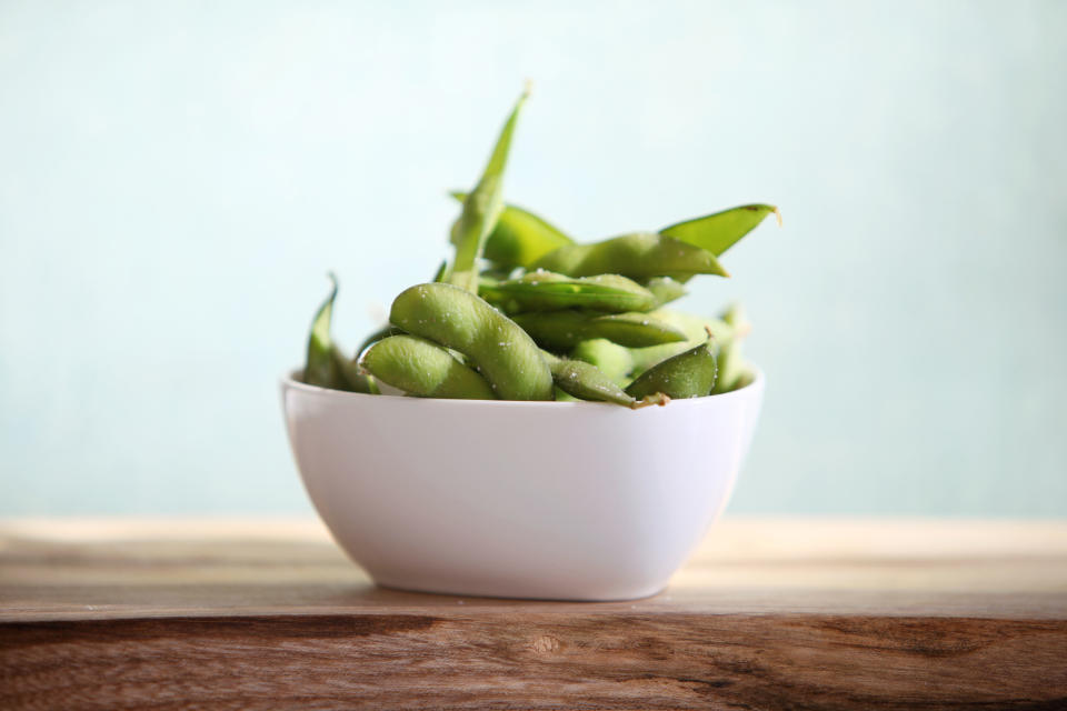A bowl of Edam soy beans in the pod, sitting on a wood board.