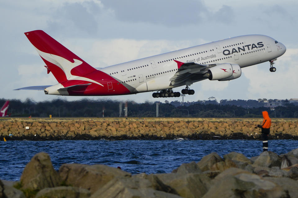 FILE - A Qantas A380 takes off from Sydney Airport over Botany Bay as a fisherman stands on breakwater in Sydney, Australia, Monday, Sept. 5, 2022. Australian national carrier Qantas posted an underlying pre-tax half-year profit of 1.43 billion Australian dollars ($978 million) on Thursday, Feb. 23, 2023, in the airline's first return to profit since the coronavirus pandemic started three years ago. (AP Photo/Mark Baker/File)