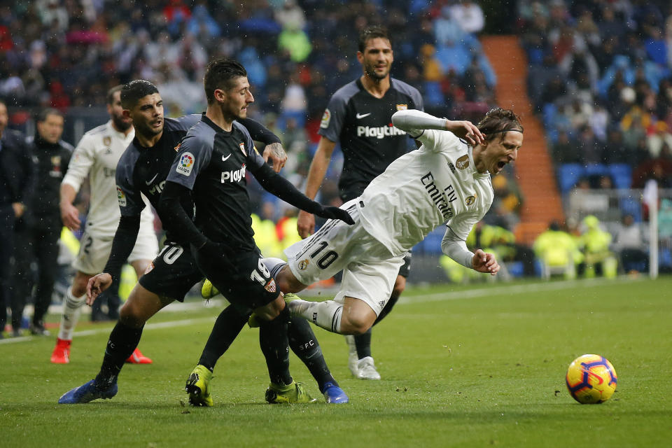 Real Madrid's Luka Modric, right, is tackled by Sevilla's Sergio Escudero during La Liga soccer match between Real Madrid and Sevilla at the Bernabeu stadium in Madrid, Spain, Saturday, Jan. 19, 2019. (AP Photo/Andrea Comas)