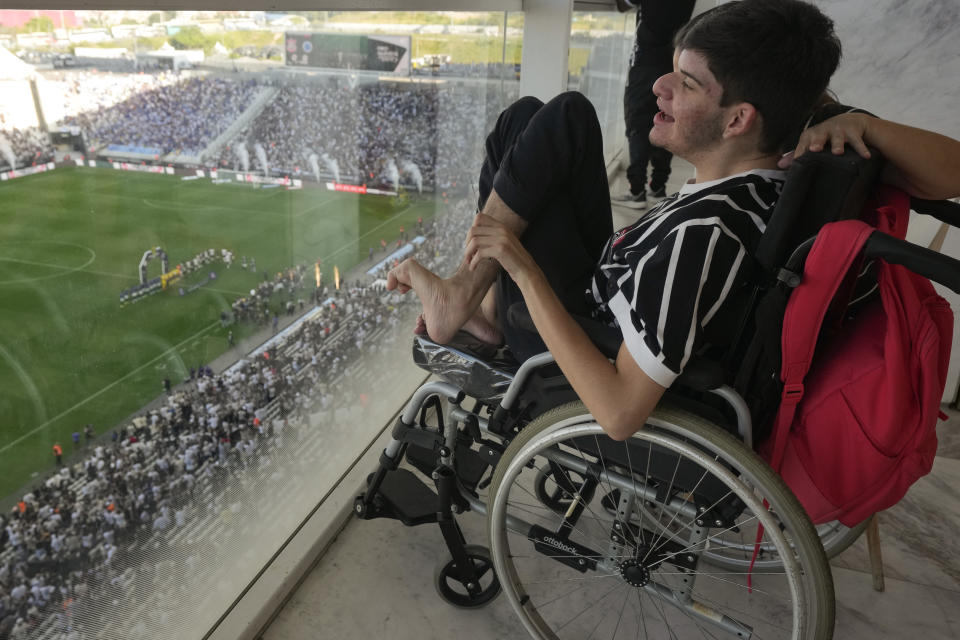 Hamilton Moreira, 16, with autism spectrum disorder, watches a Brazilian championship match between Corinthians and Cruzeiro in a special isolated room where noise impacts less, at the Neo Quimica Arena in Sao Paulo, Brazil, Sunday, April 16, 2023. Brazilian soccer clubs are increasingly opening spaces for autistic fans to watch matches, mingle and celebrate the sport, an initiative that got even higher attention in April, when Autism Speaks celebrates World Autism Awareness Month. (AP Photo/Andre Penner)