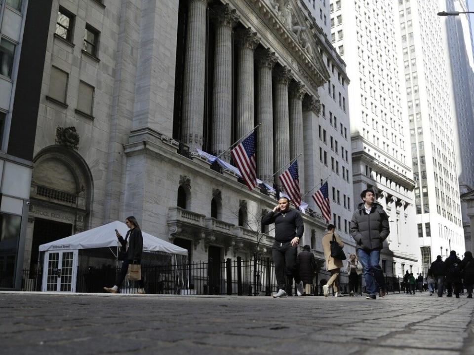  People pass in front of the New York Stock Exchange. North American stocks opened in the red on Monday.