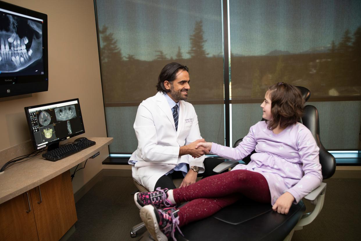 Dr. Sukhdeep Dhaliwal, oral surgeon, consults with a patient at Kitsap OMS, where beginning this summer several college students will receive free wisdom teeth extractions each year to pay tuition costs.