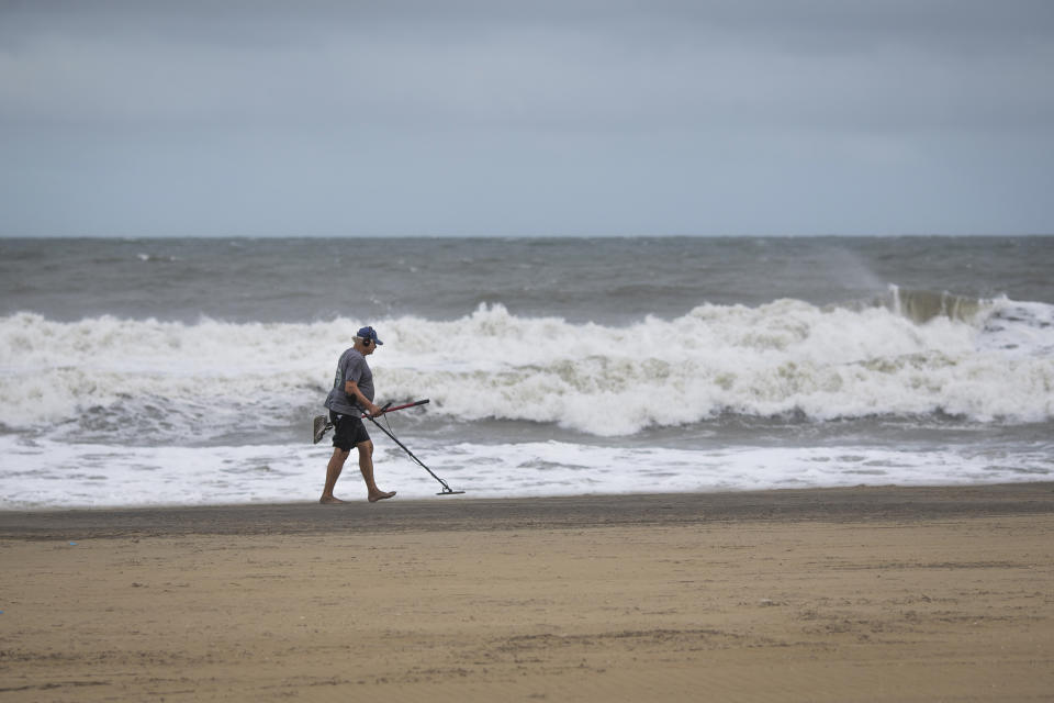 A man uses a metal detector on the Virginia Beach oceanfront during Tropical Storm Ophelia on Saturday, Sept. 23, 2023, in Virginia Beach, Va. (AP Photo/John C. Clark)