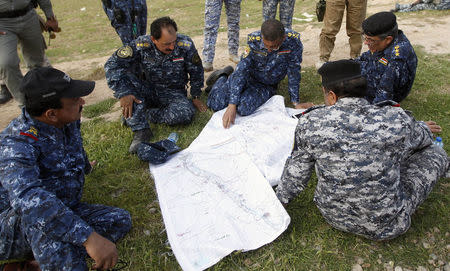 Iraqi officers inspect a map on the outskirts of al-Alam March 8, 2015. REUTERS/Thaier Al-Sudani