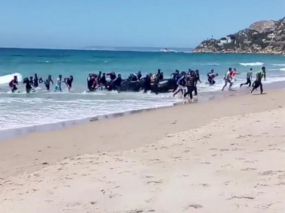 Beachgoers in Cadiz in southern Spain were surprised to see two dozen refugees disembark from a dinghy (AP)