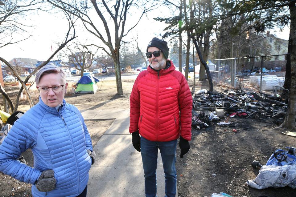 The Rev. Eliza Tweedy, left, and Geoff Day of the First Church Congregational in Rochester, talk about the obstacles facing homeless people who have been staying at an encampment on church property, as seen Wednesday, Jan. 3, 2023. In the background is a campsite which caught fire and was destroyed over the weekend.