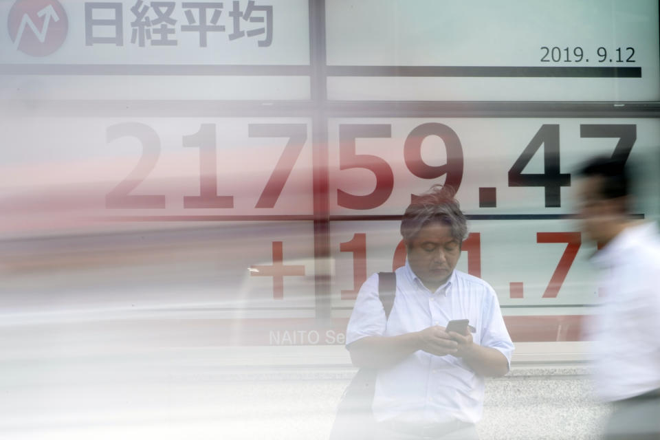 A man stands near an electronic stock board showing Japan's Nikkei 225 index at a securities firm in Tokyo Thursday, Sept. 12, 2019. Asian shares were mixed Thursday after China moved to ease trade tensions. (AP Photo/Eugene Hoshiko)