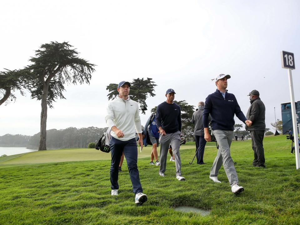 Rory McIlroy marches off the 18th green alongside Justin Thomas and Tiger Woods: Getty