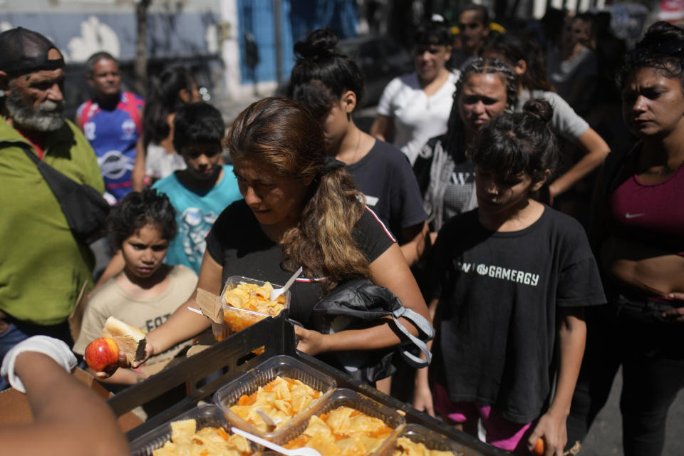 La gente recibe comidas calientes gratuitas en un comedor comunitario dirigido por el Movimiento de Trabajadores Excluidos (MTE) en Buenos Aires, Argentina, el viernes 8 de marzo de 2024. (AP Foto/Natacha Pisarenko)