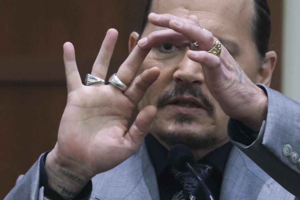 Actor Johnny Depp displays the middle finger of his hand, injured while he and his ex-wife Amber Heard were in Australia in 2015, as he testifies during a hearing in the courtroom at the Fairfax County Circuit Court in Fairfax, Va., Wednesday, April 20, 2022. Actor Johnny Depp sued his ex-wife Amber Heard for libel in Fairfax County Circuit Court after she wrote an op-ed piece in The Washington Post in 2018 referring to herself as a "public figure representing domestic abuse." (Evelyn Hockstein/Pool via AP)