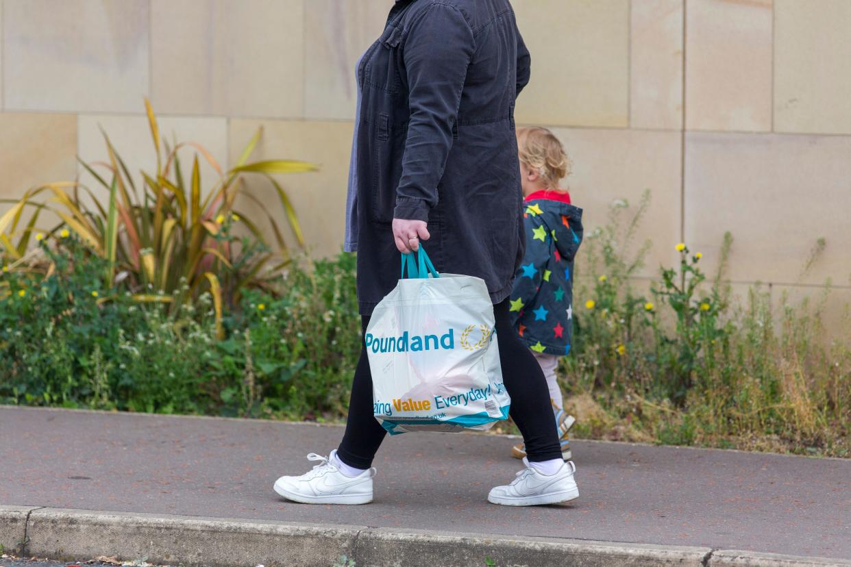 A mother and child walking with a Poundland shopping bag in Halifax, West Yorkshire, UK, as the cost of living increases