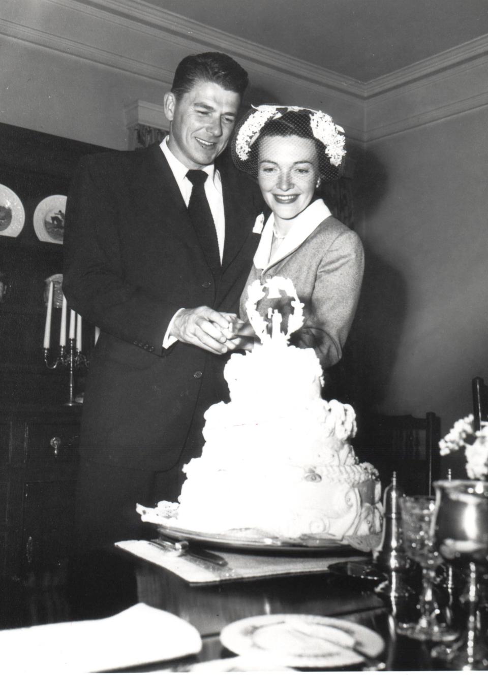 Ronald and Nancy Reagan cut their wedding cake together.