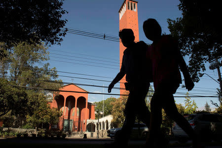 People walks past the 'El Bosque' church, former parish of Vatican-convicted child abuser Fernando Karadima, while the Vatican special envoy, Archbishop Charles Scicluna, meets with victims of sexual abuse, allegedly committed by members of the church in Santiago, Chile February 21, 2018. Picture taken February 21, 2018. REUTERS/Claudio Santana