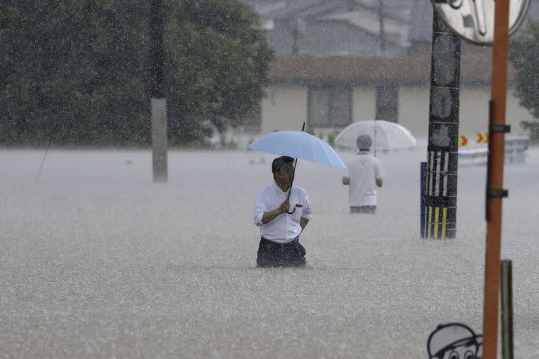 Personas caminan en una calle inundada por las fuertes lluvias, el lunes 10 de julio de 2023, en Kurume, en la prefectura de Fukuoka, en el sur de Japón.