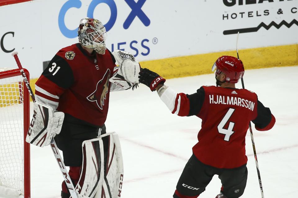 Arizona Coyotes goaltender Adin Hill (31) celebrates a win against the San Jose Sharks with Coyotes defenseman Niklas Hjalmarsson (4) as time expires in the third period of an NHL hockey game Tuesday, Jan. 14, 2020, in Glendale, Ariz. The Coyotes defeated the Sharks 6-3. (AP Photo/Ross D. Franklin)