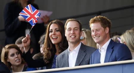 Britain's Catherine, Duchess of Cambridge waves a Union Flag as she watches with Princes William (2nd R) and Harry (R) during the Diamond Jubilee concert in front of Buckingham Palace in London June 4, 2012. REUTERS/Dave Thompson