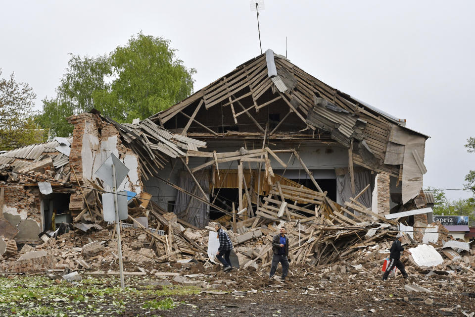 Men walk past a damaged building after Russian shelling in Soledar, Donetsk region, Ukraine, Wednesday, May 18, 2022. (AP Photo/Andriy Andriyenko)