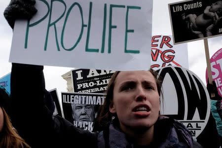 A counter-protester holds an anti-Trump sign behind a pro-life demonstrator as the annual March for Life concludes at the U.S. Supreme Court in Washington, DC, U.S. January 27, 2017. REUTERS/James Lawler Duggan