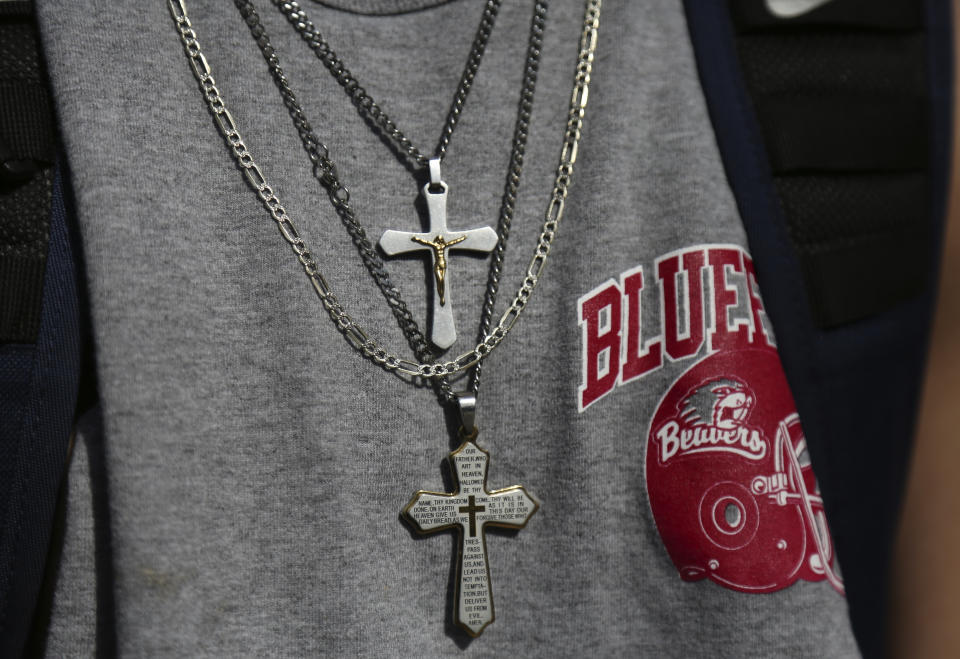 A student wears a pair of cross necklaces over a Bluefield High School football shirt while walking home in Bluefield, W.Va., on Tuesday, Jan. 24, 2021. Members of three congregations in a small city in West Virginia’s ‘Trump Country’ face a reckoning over Christianity and the misuse of symbols of their faith in America’s divisive politics. (AP Photo/Jessie Wardarski)