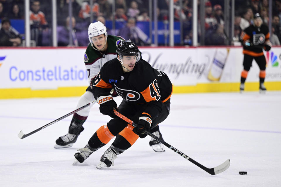 Philadelphia Flyers' Morgan Frost skates with the puck past the defense of Arizona Coyotes' Nick Bjugstad, left, during the first period of an NHL hockey game, Monday, Feb. 12, 2024, in Philadelphia. (AP Photo/Derik Hamilton)