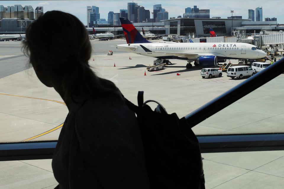 In this file photo, a traveler passes a Delta Airlines plane, which sits on the tarmac at Logan Airport in Boston, Massachusetts, U.S., June 30, 2022.