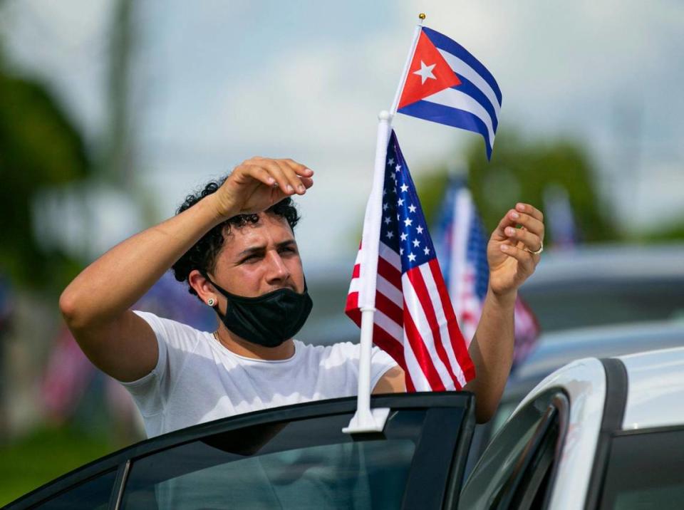 Yoandry Mora, 22, hangs flags from his car before the start of a Cubans Con Biden caravan at Bright Park in Hialeah, Florida, on Saturday, September 19, 2020.