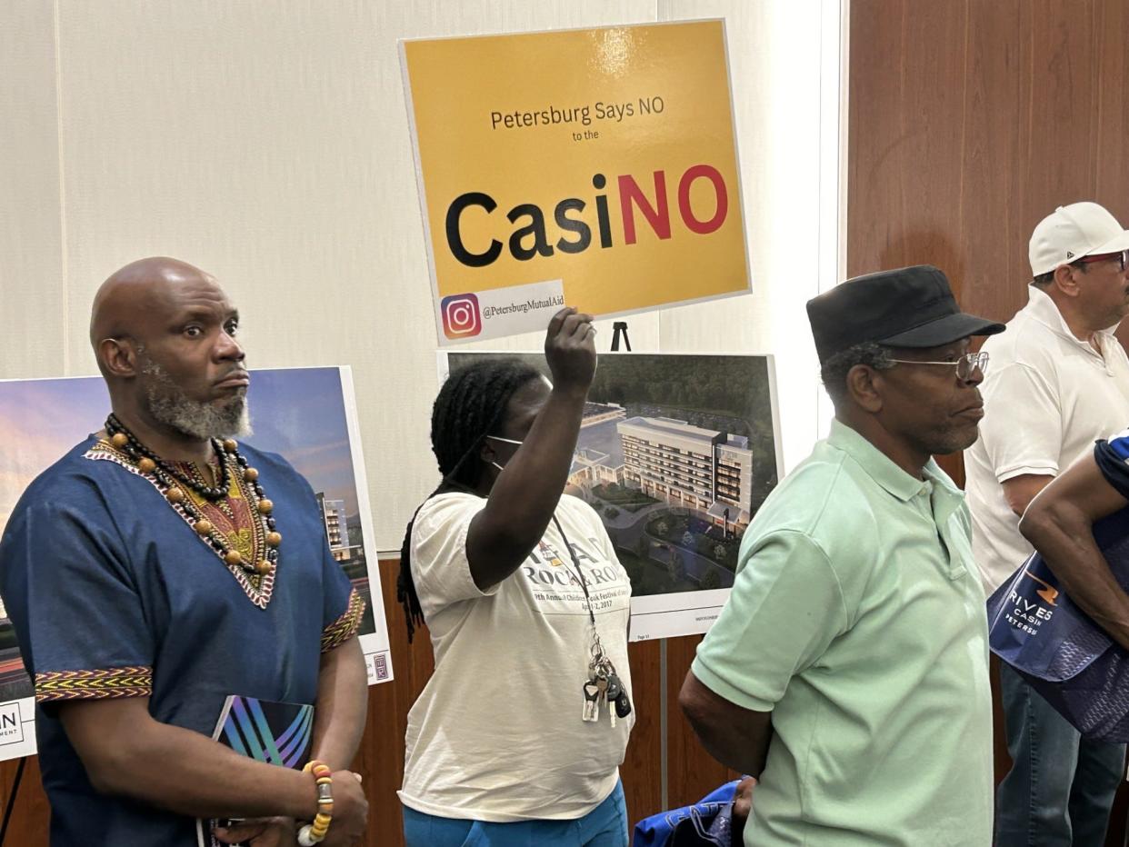 Petersburg resident Vannay Kirkland holds up a sign reading 'CasiNO' at a town hall meeting Sunday, April 14, 2024, at the Petersburg Public Library. The auditorium is filled to capacity as the five vendors make their pitches for the business.