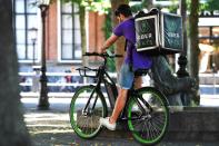 A bicycle courier from Uber Eats checks his phone in the shadow during the heatwave in Utrecht