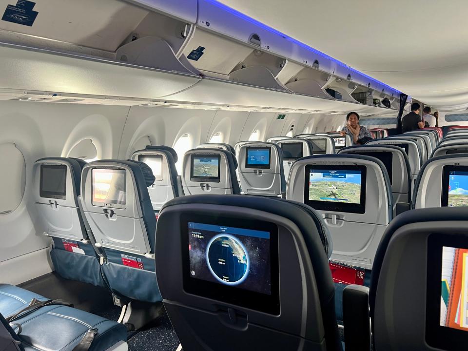 A woman standing in a Delta airplane cabin.