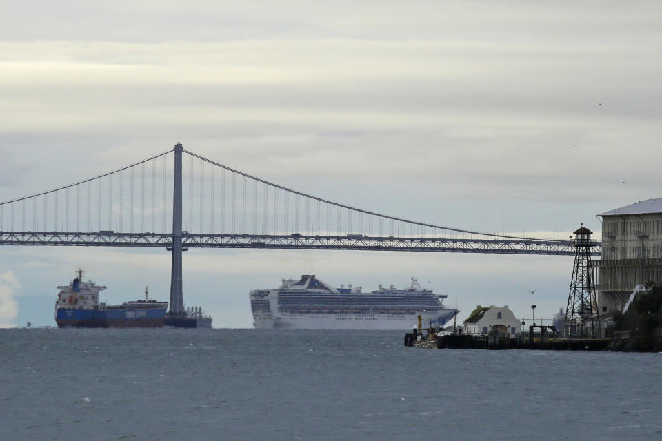 Framed by the San Francisco-Oakland Bay Bridge and Alcatraz Island, the Grand Princess cruise ship makes its way to an anchorage Monday, March 16, 2020, in San Francisco. The coronavirus-stricken cruise ship has left the Port of Oakland after a week and is moving to an anchorage in San Francisco, where it'll stay temporarily for remaining crew members and six passengers to complete a 14-day-quarantine. According to the World Health Organization, most people recover in about two to six weeks, depending on the severity of the illness. (AP Photo/Eric Risberg)