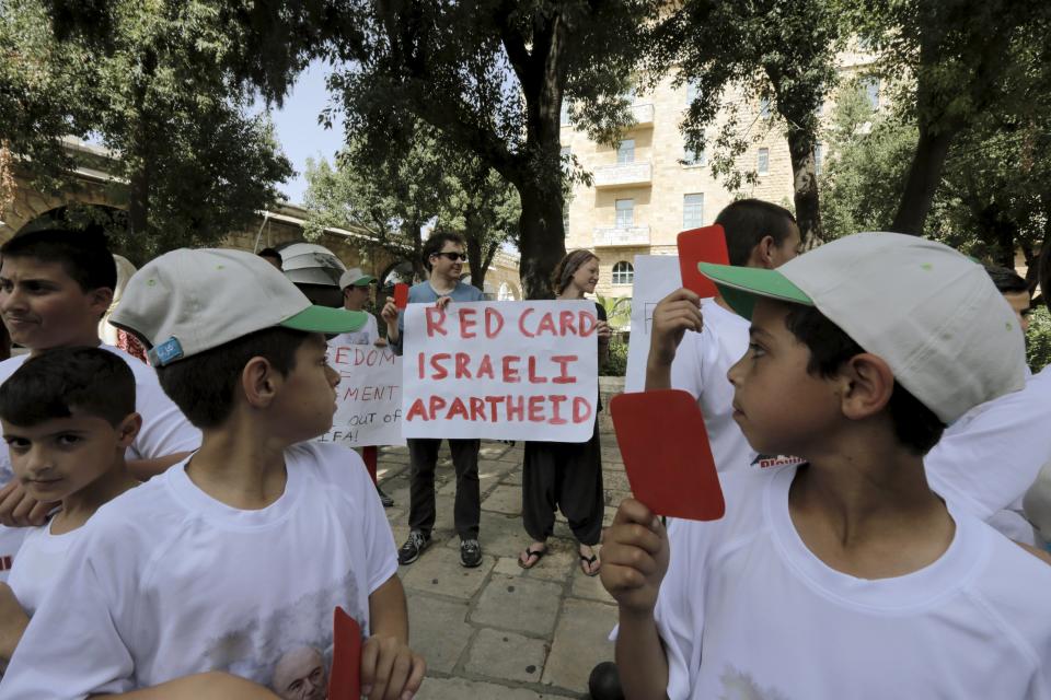 Palestinian children hold red cards during a protest held upon the arrival of FIFA president Sepp Blatter to his hotel in Jerusalem