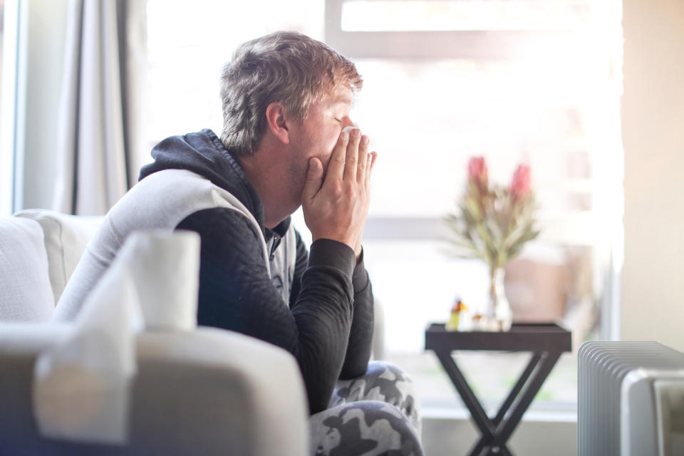 A male adult looking worried on the couch at home.