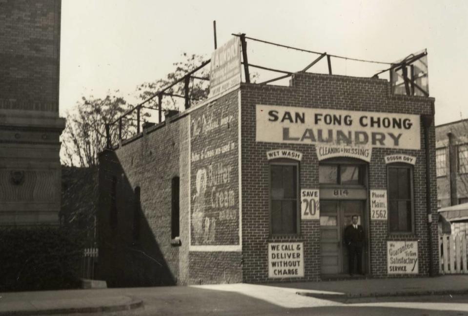 A man stands in the entry of the San Fong Chong Laundry at 814 I Street in 1935. The site is now occupied by an addition to the Sacramento Library, a portion of which is visible at left.