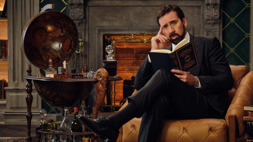 Nicolas Cage sits on a chair reading a book. Nicolas Cage plans to never retire.